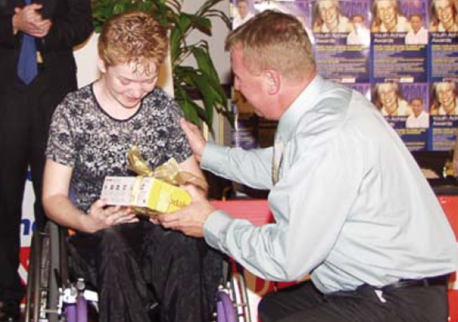 Chairperson, Trevor Castle, handing an award to a winner at the Youth Achievement Awards in 2004.